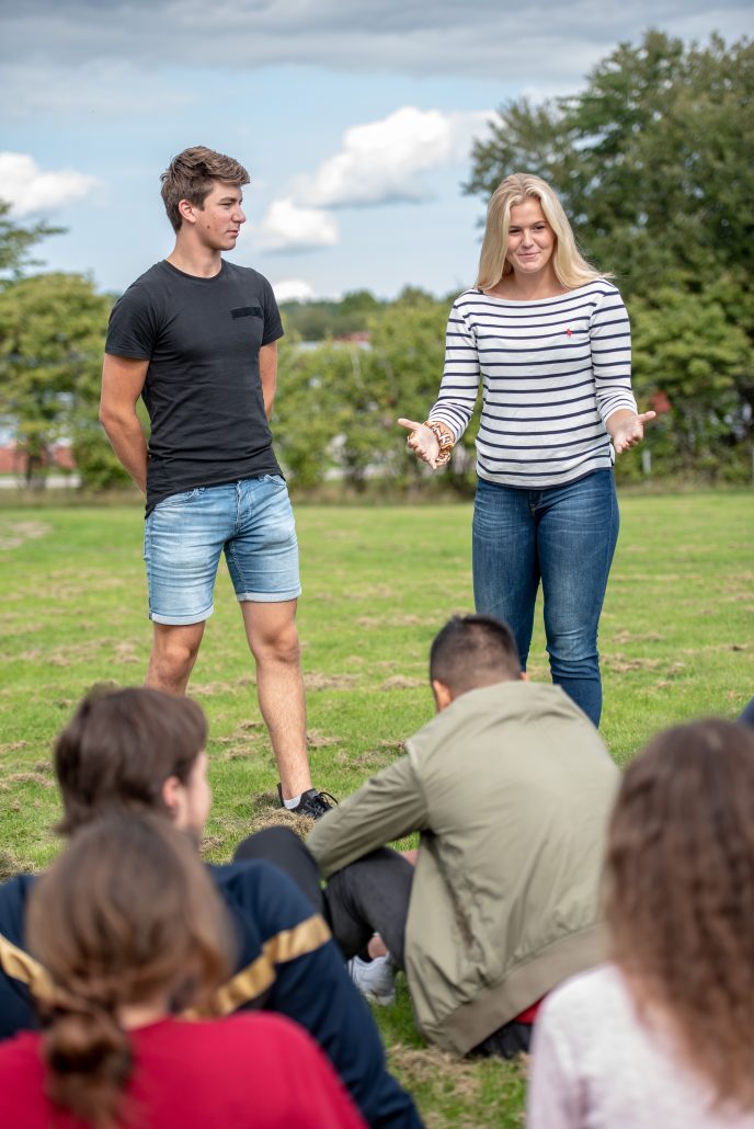 Ung man och kvinna instruerar en grupp ungdomar