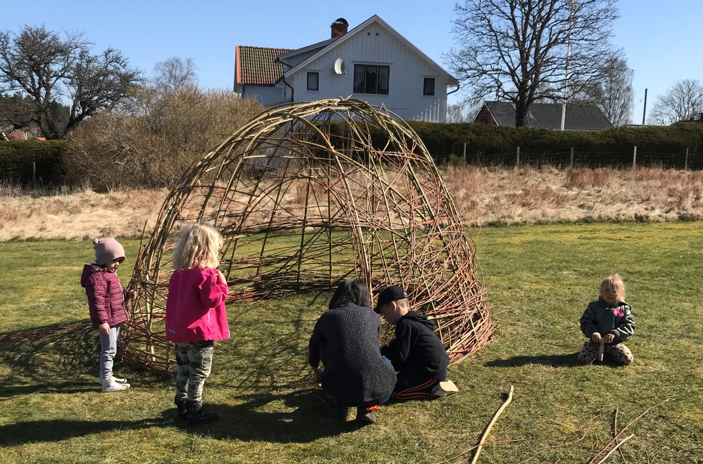 Förskolebarn som bygger en pilkoja utomhus.