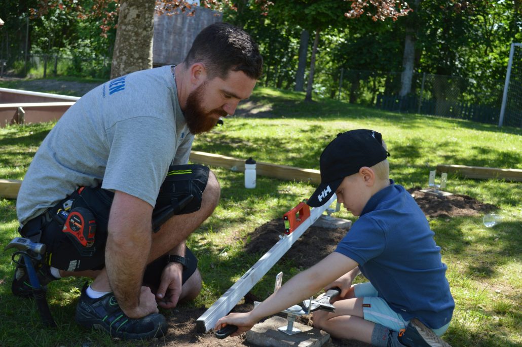 En man och en förskolepojke mäter så att bygget blir rakt.