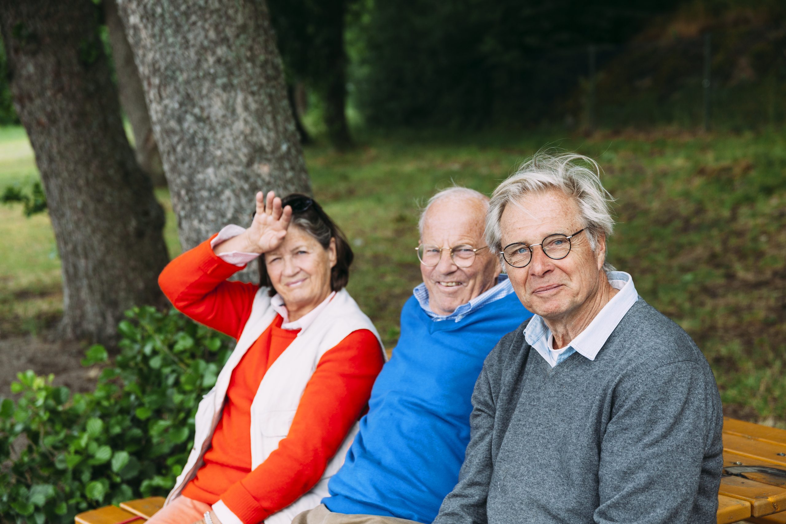 Tre äldre människor sitter tillsammans på en bänk