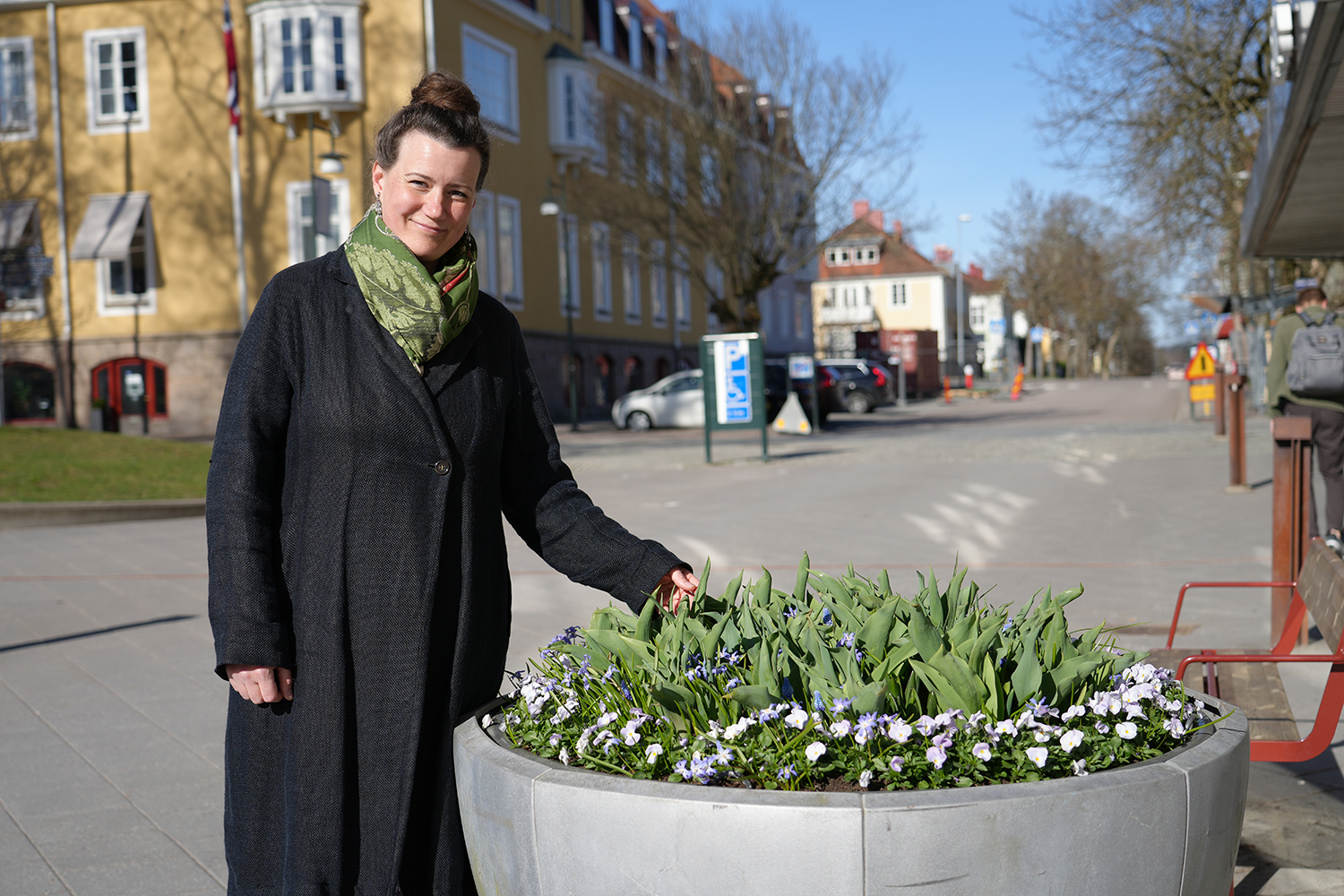 Karolina Alvaker står bredvid en urna med blommor utanför kulturhuset.