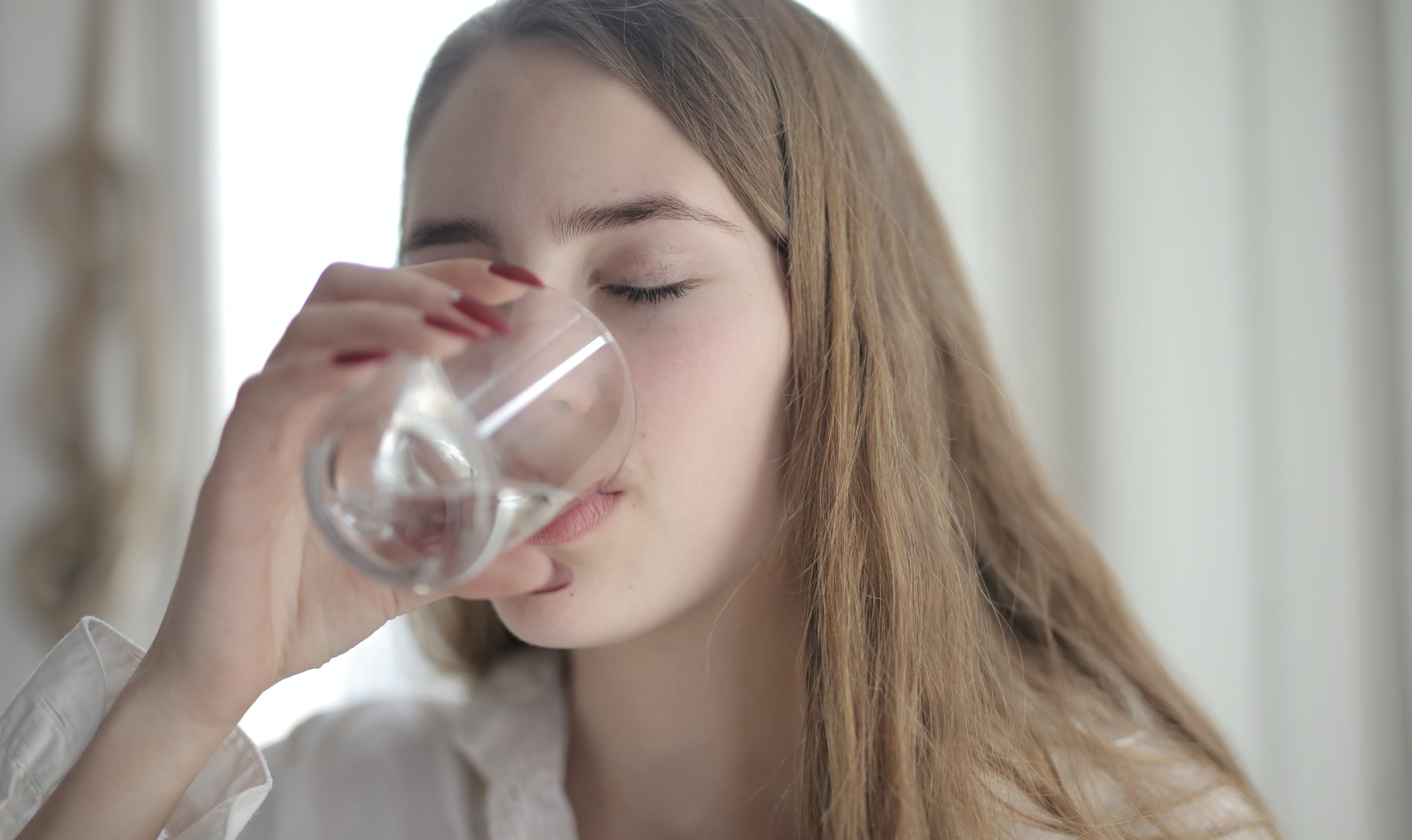 Kvinna som dricker ett glas vatten.